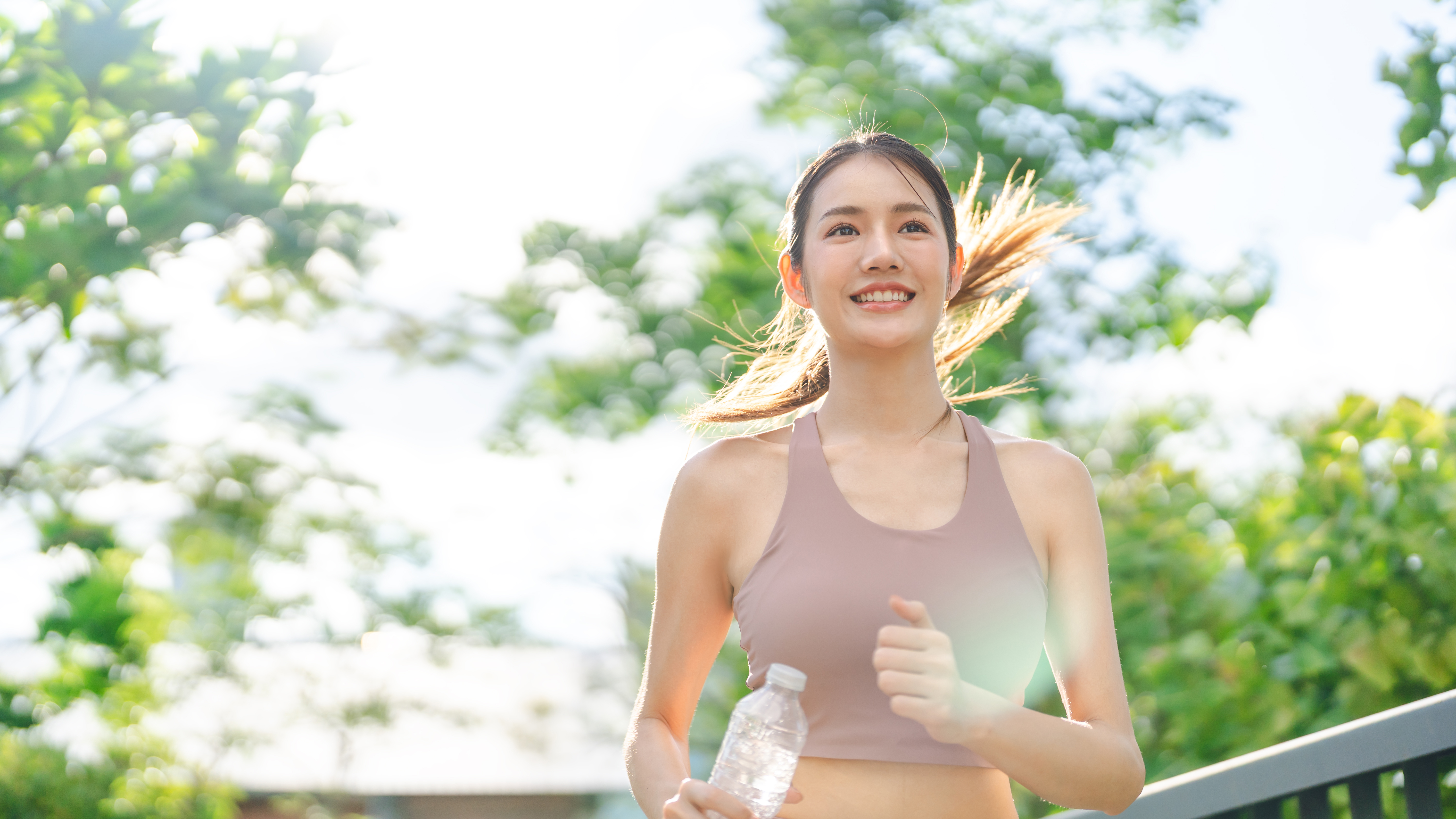 パーソナルジムでトレーナーとフォームを確認する女性